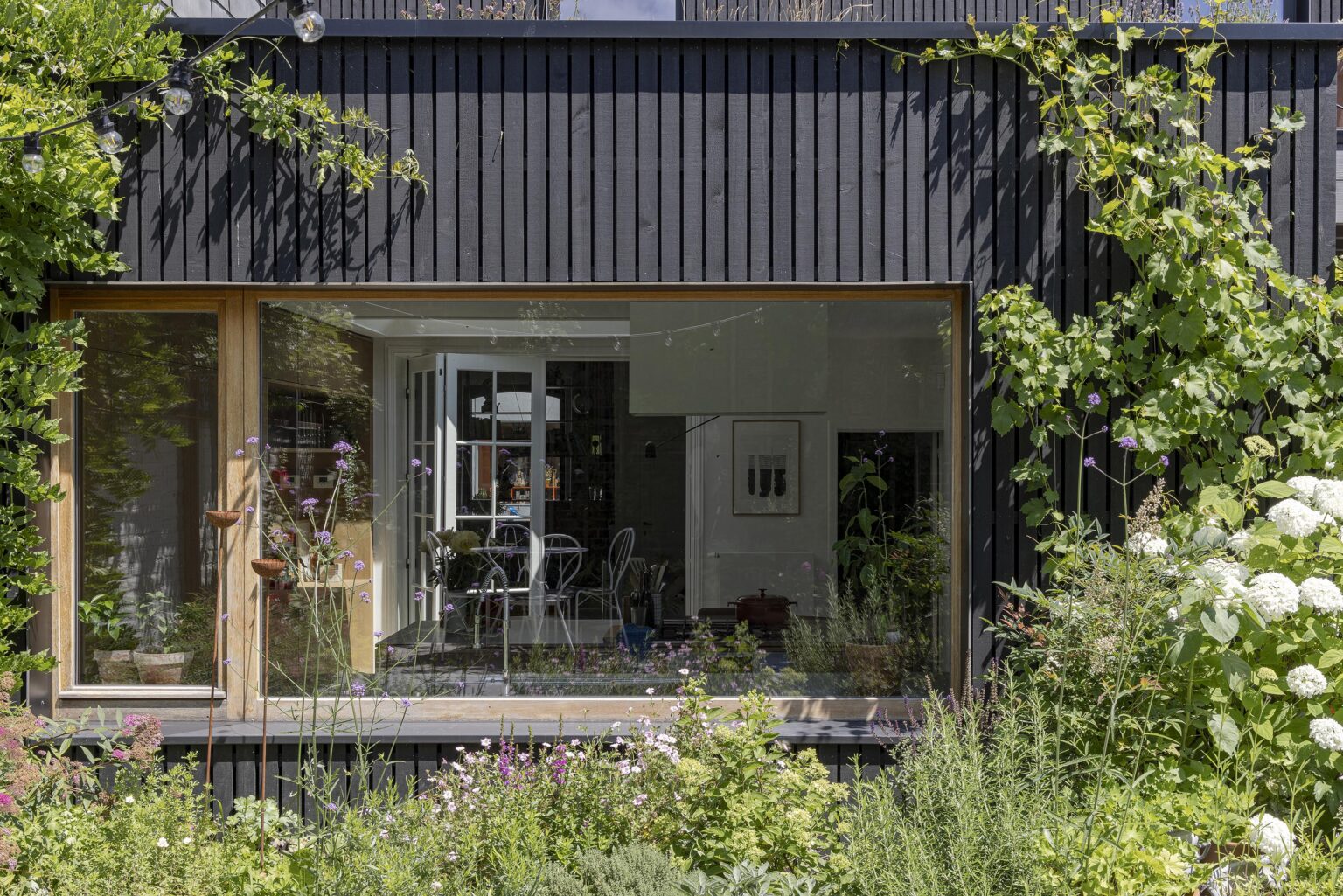 Baie vitrée encadrée de bois donnant sur un jardin fleuri.
